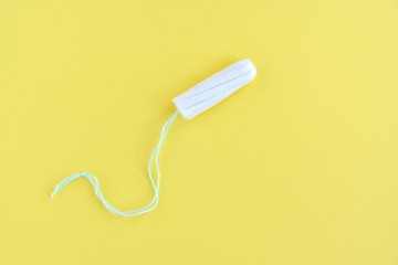 Soft cotton tampon for women period days with selective focus on yellow background. Hygiene products for women's monthly menstruation. White protection tampons for female health care. Copy space - obrazy, fototapety, plakaty