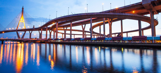 Naklejka na ściany i meble Panoramic landscape of highway interchange and suspension bridges at dusk.