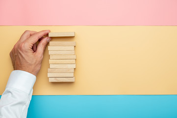 Top view of male hand making a stack of wooden blocks