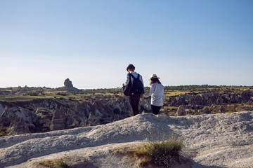 guy with a girl in hats and a backpack are on the rocks