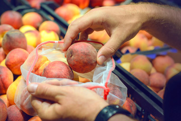 Zero waste, plastic free recycled  produce bag for carrying fruit..Buying peaches in the grocery mesh