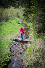 Obraz premium The girl in the red jacket photographs the stream
