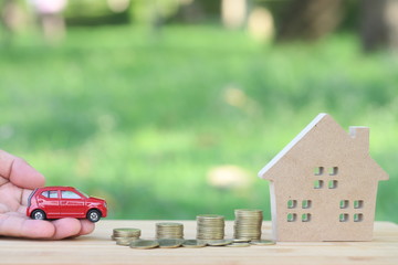 Home and red  car models with coins for home and car in the family.Use money to exchange or buy in...