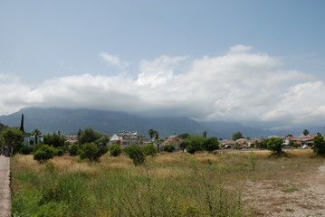 Obraz premium Clouds descend below the mountain peaks above the mountain city.