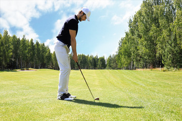 Full length of golf player playing golf on sunny day. Professional male golfer taking shot on golf...