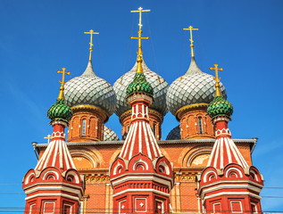 Fototapeta na wymiar Domes and crosses of ancient orthodox temple against blue sky