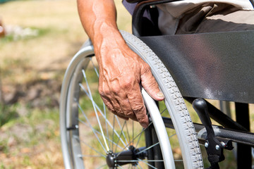 A disabled man is sitting in a wheelchair ,Holds his hands on the wheel. Handicap people Concept.