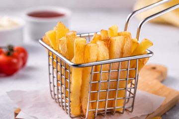 French fries in a basket on a modern white concrete background