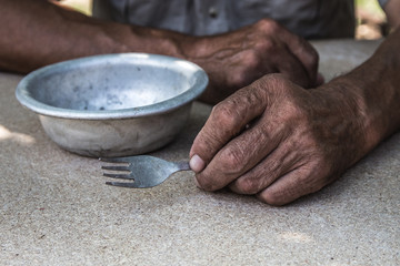 Hungry. Poor old man's hands an empty bowl. Selective focus. Poverty in retirement. Alms