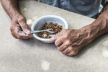 Hungry. Poor old man's hands an bowl of porridge . Selective focus. Poverty in retirement.
