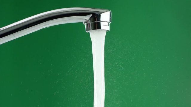 water flows from the tap on a green background, splashes are visible