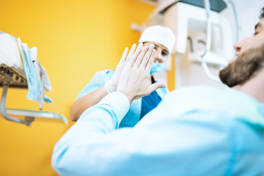 Giovane ragazza dentista odontoiatra da il cinque con la mano al paziente dopo l'operazione ai denti. Rapporto di fiducia ed esperienza.