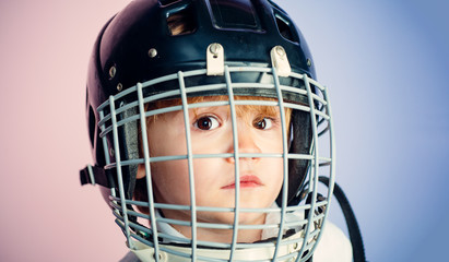 Fototapeta na wymiar Boy cute child wear hockey helmet close up. Safety and protection. Protective grid on face. Sport equipment. Hockey or rugby helmet. Sport childhood. Future sport star. Sport upbringing and career