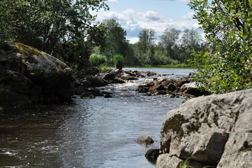 Old destroyed dam on the lake - a fast stream of water flows through large stones