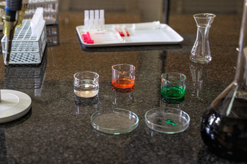 Pipette and colourful chemical liquid solutions in flasks on laboratory worktop