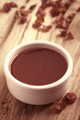 Homemade rose hip jam in bowl with dried rosehip on the side, photographed on wood with natural light (Selective Focus, Focus in the middle of the jam) (Digitally Altered: Toned Image)