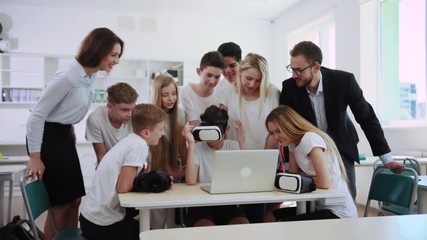Amazing virtual reality experience at a lesson. Excited teachers and their students looking at boy wearing VR headset educating with 3D technologies.