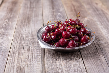 Fresh ripe black cherries in a metal bowl on a grey wooden background Image