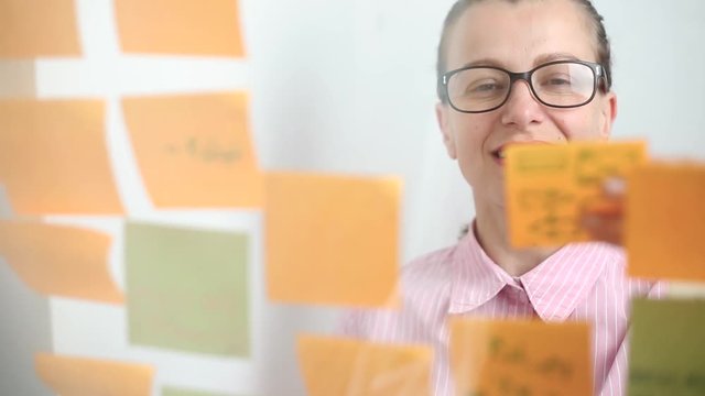 Smiling business woman writing down her ideas and notes on stickers. Brainstorm.