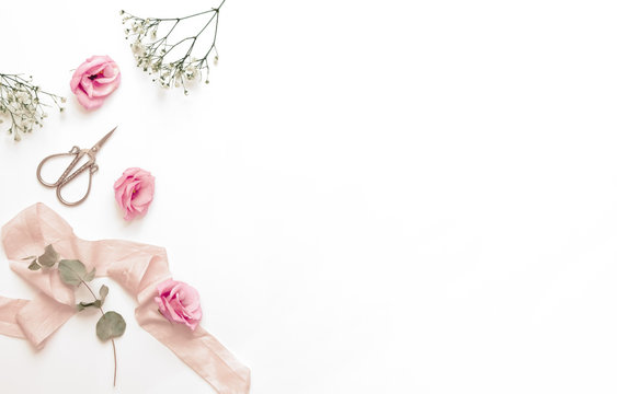 Feminine, styled flatlay with pink flowers. With white space for text or product.