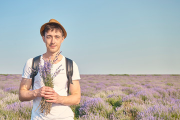 a man stands in a field of flowers with a bouquet of lavender