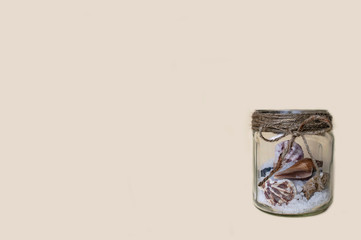 glass jar with sea salt and shells yellow background
