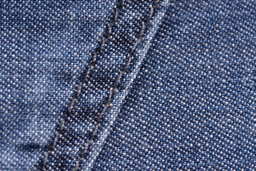 Blue denim. Cotton fabric, jeans. Creative vintage background. Pocket and zipper. The line is of poor quality. Cheap item.