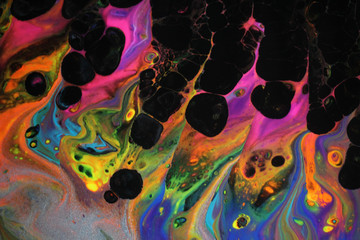 Abstract acrylic pour painting in vibrant retro neon colors and black cells popping up which...
