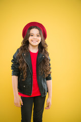 Positively about her look. fashionable little girl. kid fashion. child on yellow background. small girl kid with long curly hair. happy girl in french beret and leather jacket. parisian fashion girl