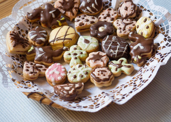 Close up detail of traditional Czech Christmas or Easter sweets, Linzer cookies stuffed with strawberry jam painted with colorful icing, served on plate, selective focus.
