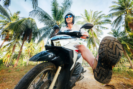 Man in safe helmet riding motor bike in jungle