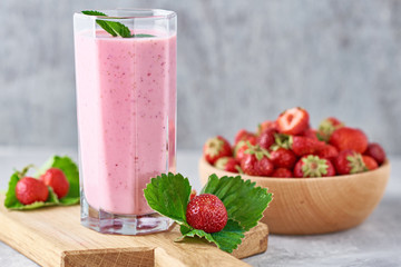 Strawberry milk shake in a glass jar and fresh strawberries with leaves