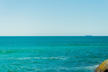 Vista de um grande navio navegando no horizonte do oceano Atlântico e uma encosta.