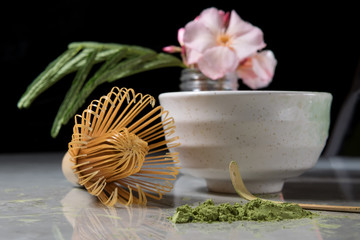 Organic tea matcha latte with bamboo chasen and bamboo spoon in a bowl on gray marble with...