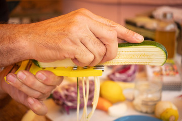 Caucasian hands of a man cutting vegetables with a new kitchen tool. One people only, large selection of vegetables