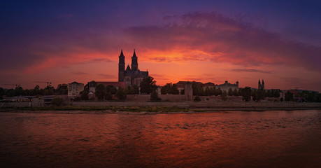 Naklejka na ściany i meble Panoramic view of bloody sunset in front of cathedral in Magdeburg and river Elbe, Germany, Summer