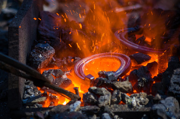 blacksmith furnace with burning coals, tools, and glowing hot horseshoe