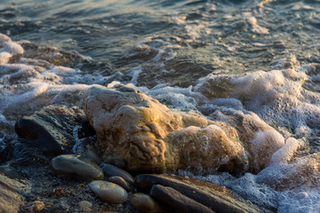 pebble stones on the sea beach, the rolling waves of the sea with foam