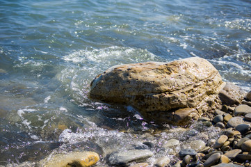 pebble stones on the sea beach, the rolling waves of the sea with foam