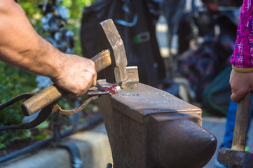 blacksmith performs the forging of hot glowing metal on the anvil