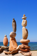 Three Rock zen pyramids of colorful pebbles standing on the beach, on the background of the sea....