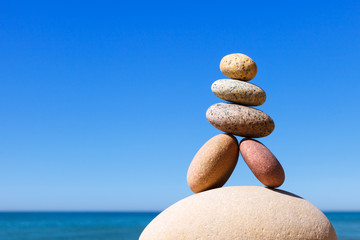 Rock zen pyramid of colorful pebbles on a beach on the background of the sea.