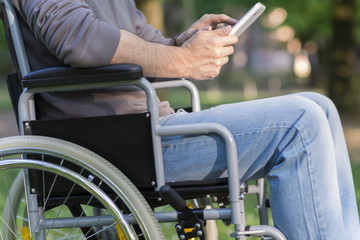 Detail of disabled man using a tablet in a park