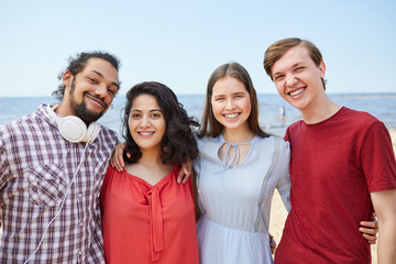 Four happy young people posing at beach enjoying Summer, copy space