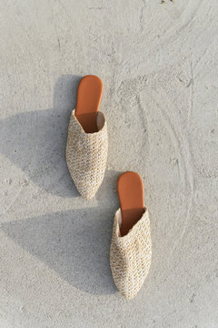 Beige Fashion Wicker Mules On The Background Of Asphalt And Concrete. Stylish, Summer And Trend Shoes