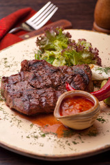 Well-dWell-done steak with suace and vagetables. Reastaurant dishes on the wooden table. Food photo for restaurant menu. Selective fone steak with suace and vagetables. Food photo for restaurant menu.