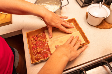 Fototapeta na wymiar Preparing lasagna in a home kitchen. Cooking homemade meals for the household.