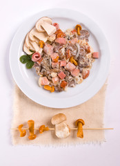 Mushroom salad with white mushrooms, honey agaric, bacon, served with parmesan cheese on white plate. 