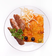 Cheese casserole with slises of grilled meat on white background on a transparent plate, close up.