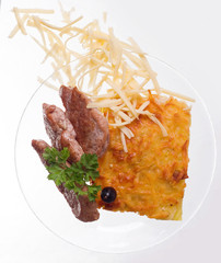 Cheese casserole with slises of grilled meat on white background on a transparent plate, close up.